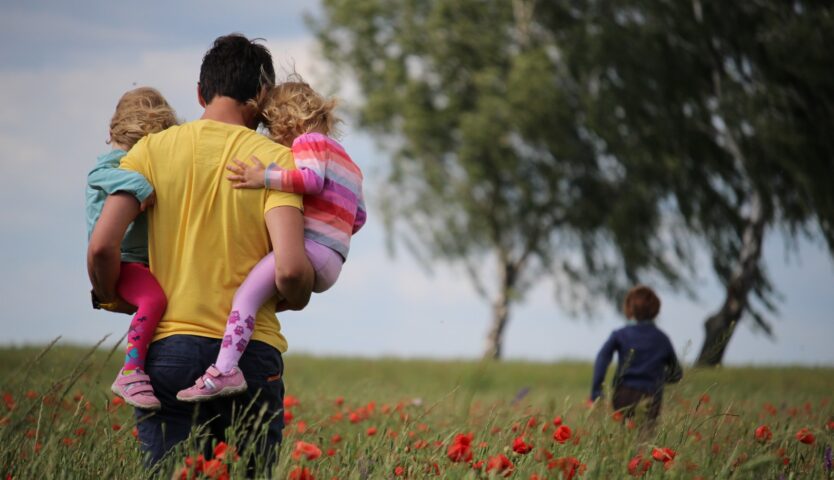 father-carying-his-kids-through-a-field