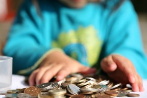 child's hands playing with a pile of coins