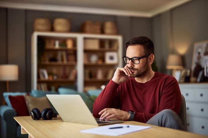 Man working on a laptop at a desk in a home office