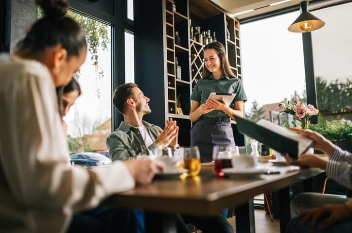 Server taking an order from customers at a restaurant table