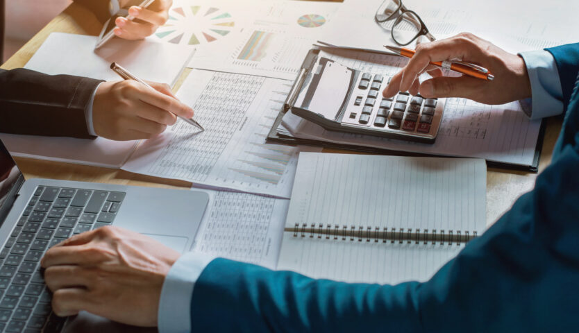 The hands of two accountants working on paper using a calculator