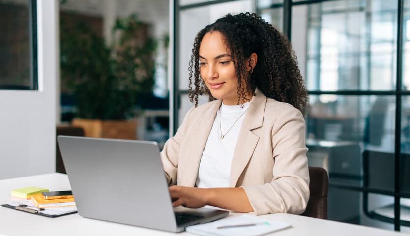 Woman working on a laptop at a desk in a modern office setting