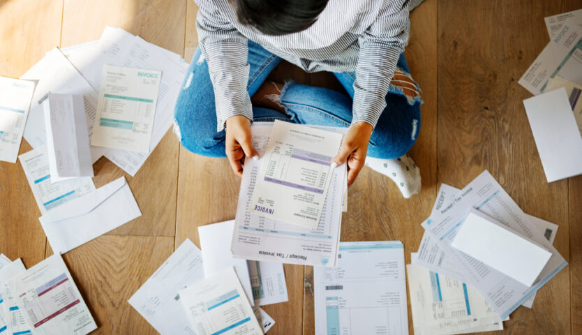 person sitting on hardwood floor amongst tax paperwork