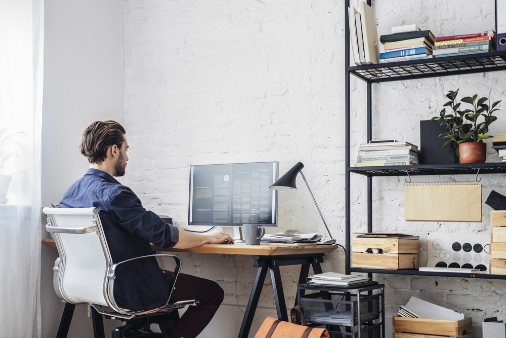 man sits in home office while working on computer