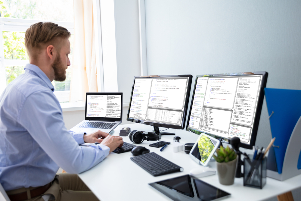 Computer programmer writing program code on computer in home office