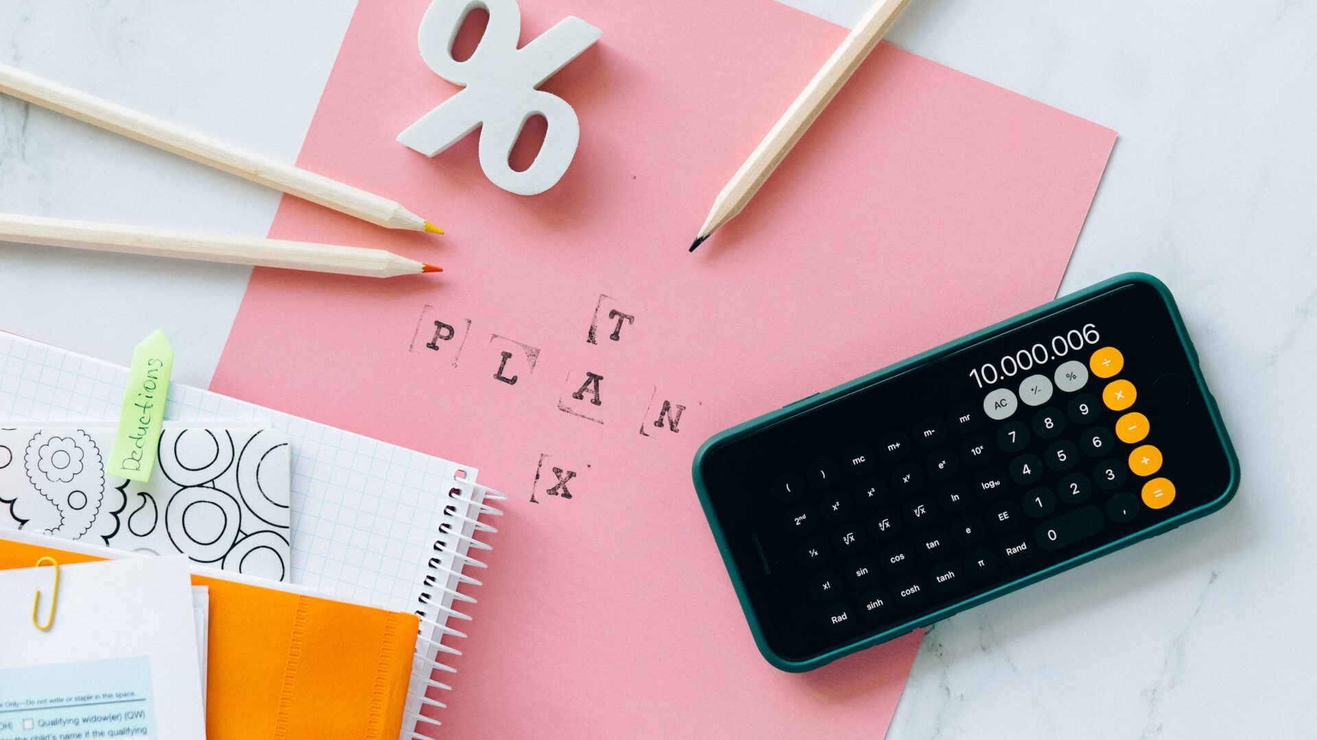 Calculator on top of pink paper that reads "tax plan"