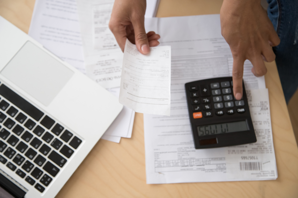 hands over a desk holding a receipt and using a calculator