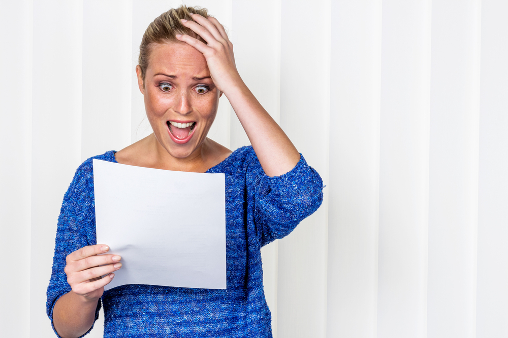 young woman with shocked expression looking at piece of paper