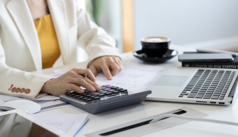 Business woman using calculator and writing make note