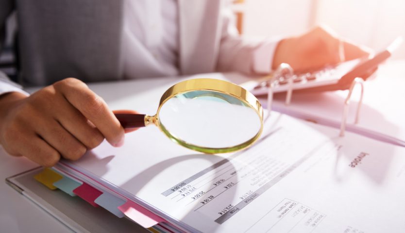 Businesswoman Analyzing Taxes With Magnifying Glass