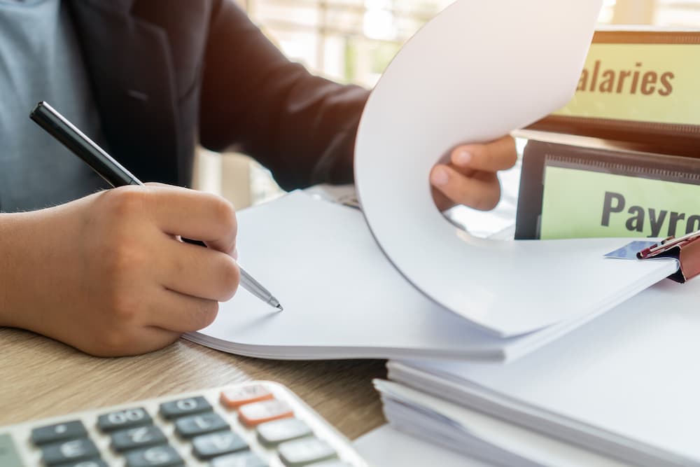 Close Up of Someone Writing on a Notepad Working on Payroll Services