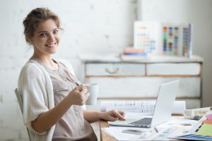 woman sitting at home office desk with cup of coffee